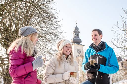Zwei Frauen und ein Mann genießen im Schnee eine Tasse Tee vom Curhaus Bad Mühllacken
